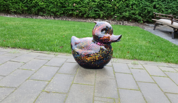 Belle een grote badeend voor je tuin. Zwart tuinbeeld in de vorm van een badeend met levendige gekleurde verfspatten, een speelse toevoeging aan de tuindecoratie.