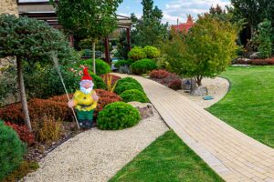 Gele tuinkabouter met bezem in tuin