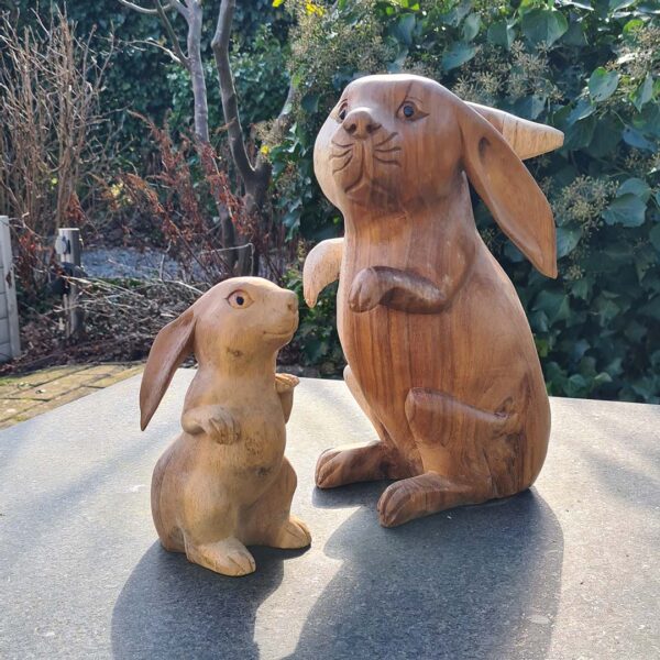 Deze houten set konijnen, handgesneden uit duurzaam suarhout, is een prachtige decoratie voor binnen en buiten. Elk exemplaar is uniek! De set bestaat uit een groot konijn (ca. 33 cm) en een klein konijn (ca. 20 cm).