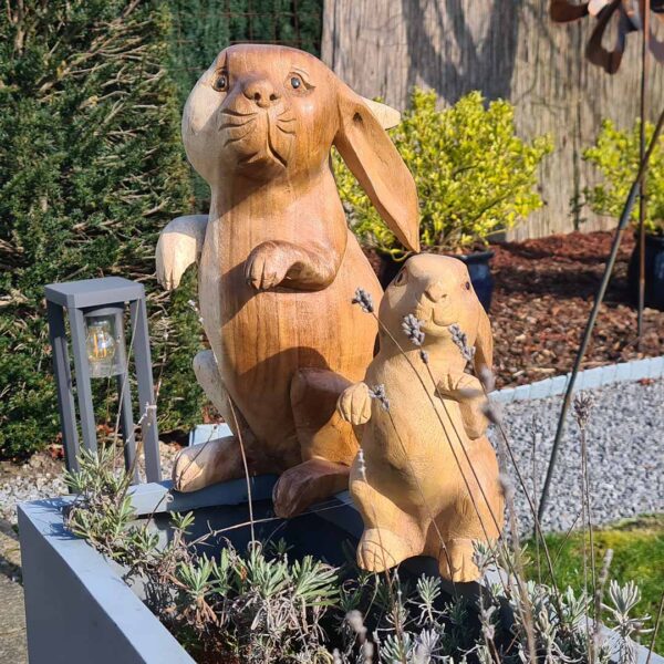 Deze houten set konijnen, handgesneden uit duurzaam suarhout, is een prachtige decoratie voor binnen en buiten. Elk exemplaar is uniek! De set bestaat uit een groot konijn (ca. 33 cm) en een klein konijn (ca. 20 cm).