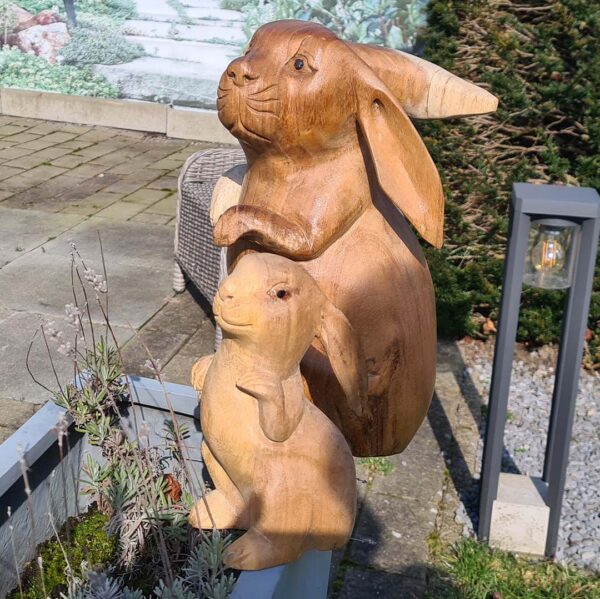 Deze houten set konijnen, handgesneden uit duurzaam suarhout, is een prachtige decoratie voor binnen en buiten. Elk exemplaar is uniek! De set bestaat uit een groot konijn (ca. 33 cm) en een klein konijn (ca. 20 cm).
