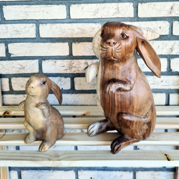 Deze houten set konijnen, handgesneden uit duurzaam suarhout, is een prachtige decoratie voor binnen en buiten. Elk exemplaar is uniek! De set bestaat uit een groot konijn (ca. 33 cm) en een klein konijn (ca. 20 cm).