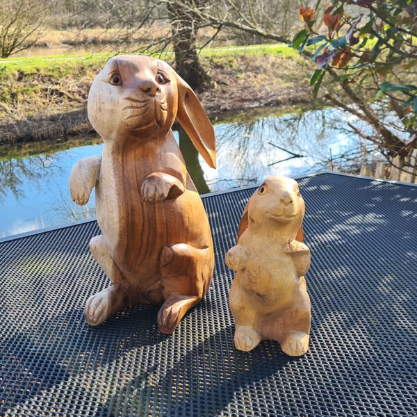 Deze houten set konijnen, handgesneden uit duurzaam suarhout, is een prachtige decoratie voor binnen en buiten. Elk exemplaar is uniek! De set bestaat uit een groot konijn (ca. 33 cm) en een klein konijn (ca. 20 cm).