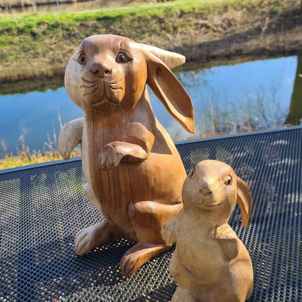 Deze houten set konijnen, handgesneden uit duurzaam suarhout, is een prachtige decoratie voor binnen en buiten. Elk exemplaar is uniek! De set bestaat uit een groot konijn (ca. 33 cm) en een klein konijn (ca. 20 cm).
