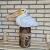 Deze houten pelikaan op een stronk (ca. 50 cm hoog) is een unieke, handgemaakte blikvanger voor binnen en buiten. Met de hand gesneden en geschilderd