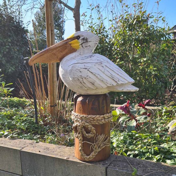 Deze houten pelikaan op een stronk (ca. 50 cm hoog) is een unieke, handgemaakte blikvanger voor binnen en buiten. Met de hand gesneden en geschilderd